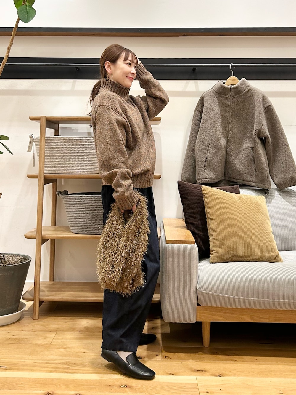 ブラウン系のニット/セーター、ブラウン系のトートバッグ、ブルー系のデニムパンツを着用したレディースの冬コーディネートの4枚目の写真