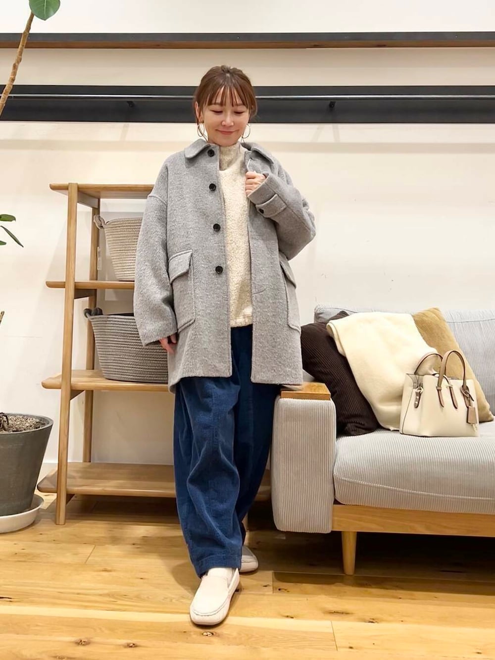 ホワイト系のハンドバッグ、グレー系のその他アウター、ホワイト系のスリッポンを着用したレディースの冬コーディネートの4枚目の写真