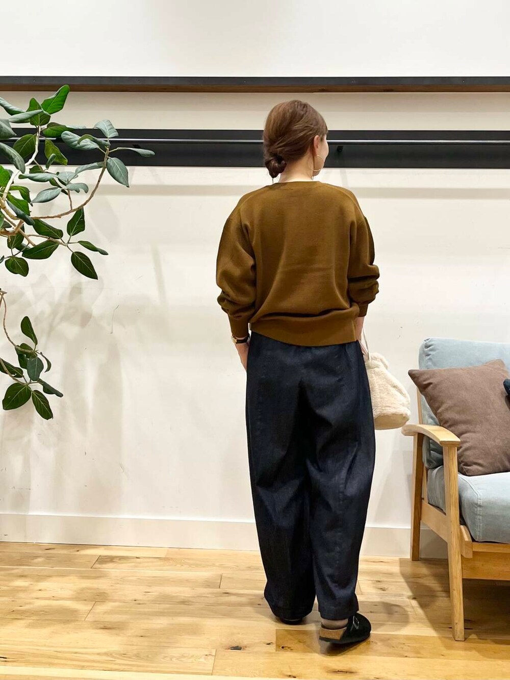 ブルー系のデニムパンツ、イエロー系のカーディガン/ボレロ、ホワイト系のショルダーバッグを着用したレディースの秋コーディネートの3枚目の写真