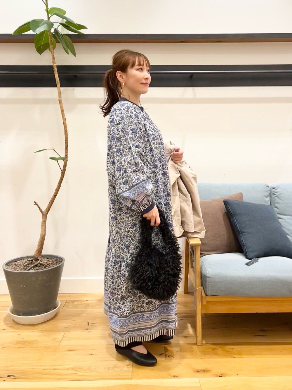 ベージュ系のマウンテンパーカー、ブルー系のワンピース、ブラック系のショルダーバッグを着用したレディースの冬コーディネートの4枚目の写真