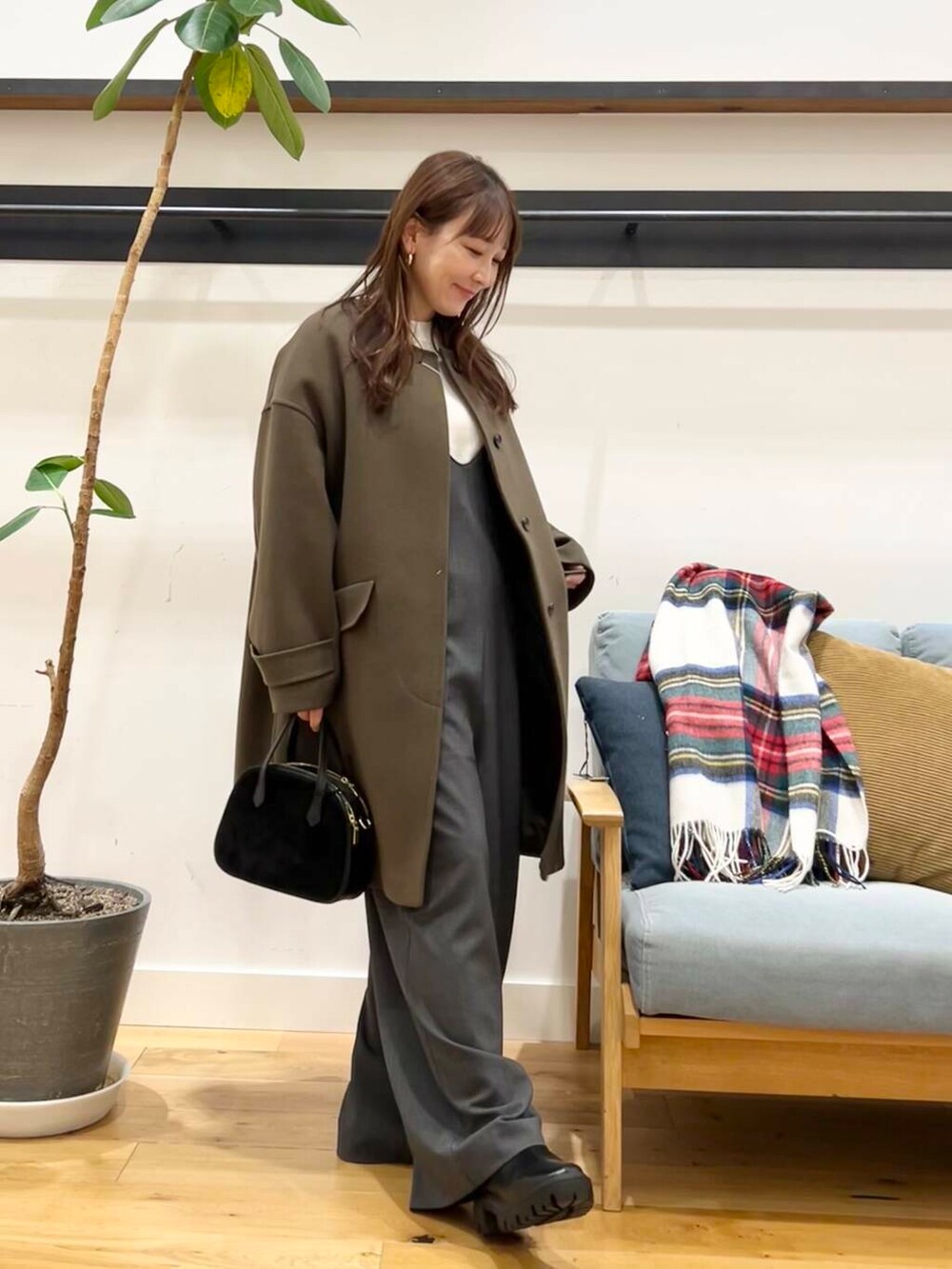 グリーン系のノーカラーコート、ホワイト系のニット/セーター、ブラック系のショルダーバッグを着用したレディースの冬コーディネートの5枚目の写真