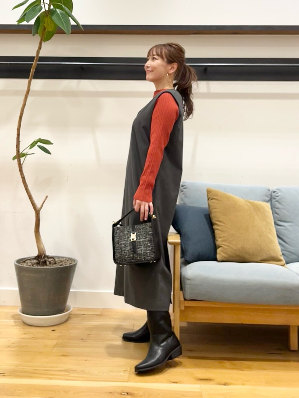 グレー系のワンピース、オレンジ系のニット/セーター、ブラック系のショルダーバッグを着用したレディースの秋コーディネートの2枚目の写真