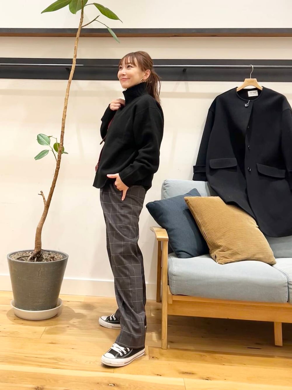 ブラック系のノーカラーコート、レッド系のショルダーバッグ、ブラック系のニット/セーターを着用したレディースの冬コーディネートの2枚目の写真