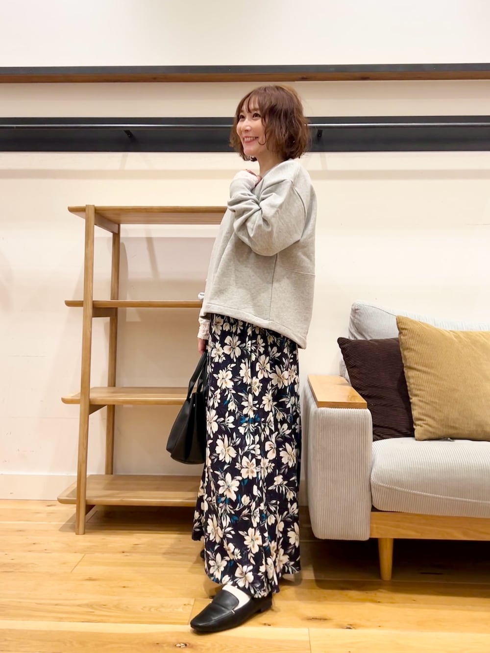 グレー系のスウェット、ブルー系のスカート、オレンジ系のトートバッグを着用したレディースの冬コーディネートの2枚目の写真