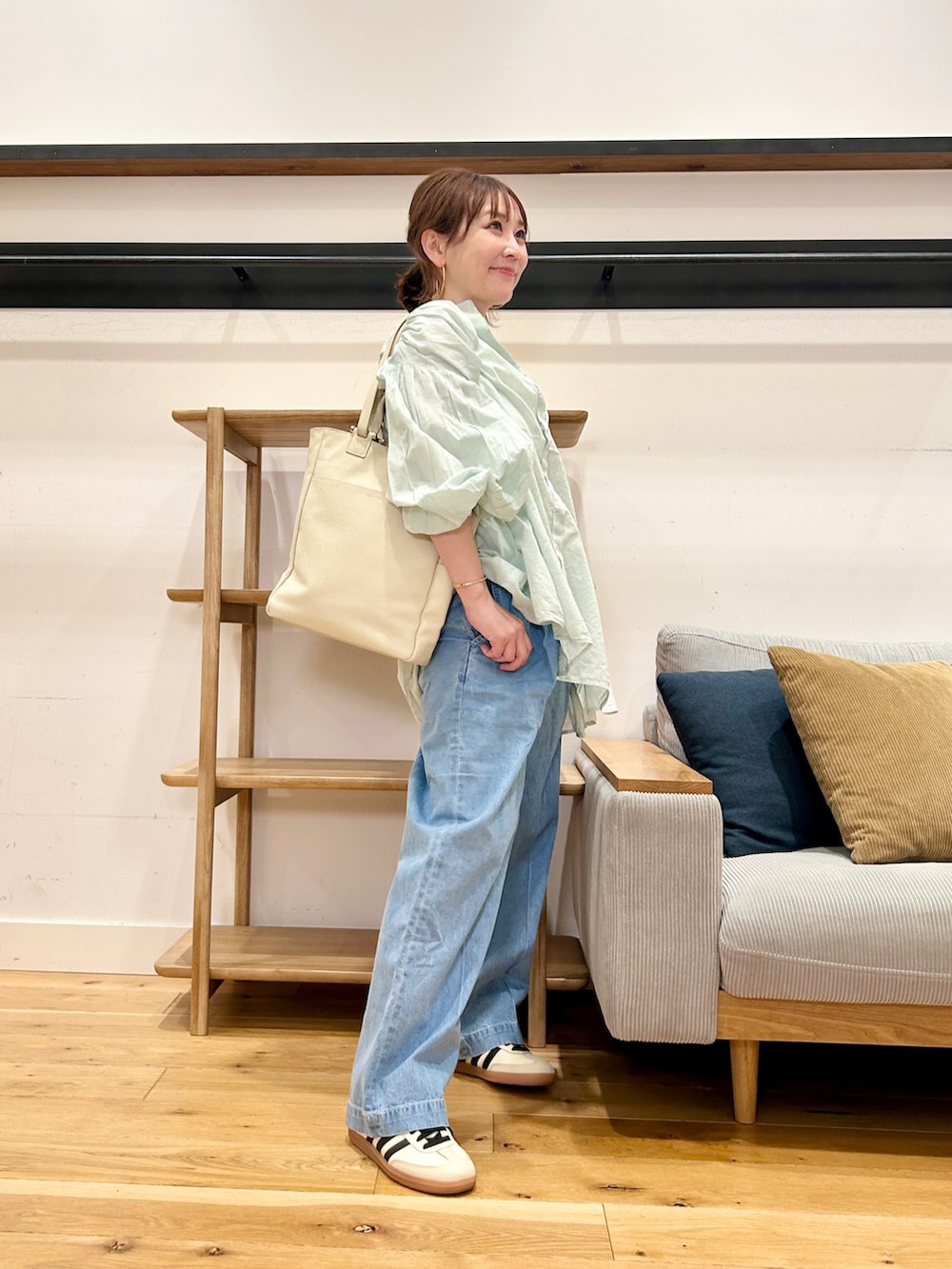 グリーン系のシャツ/ブラウス、ブルー系のデニムパンツ、ベージュ系のスニーカーを着用したレディースの春コーディネートの2枚目の写真