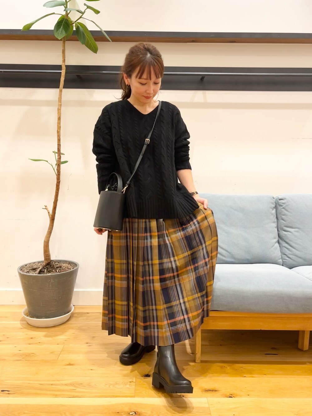 ブラック系のニット/セーター、ブルー系のスカート、ブラック系のショルダーバッグを着用したレディースの冬コーディネートの4枚目の写真