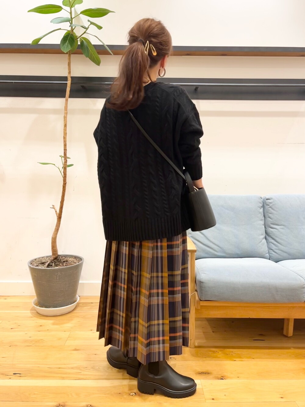 ブラック系のニット/セーター、ブルー系のスカート、ブラック系のショルダーバッグを着用したレディースの冬コーディネートの3枚目の写真