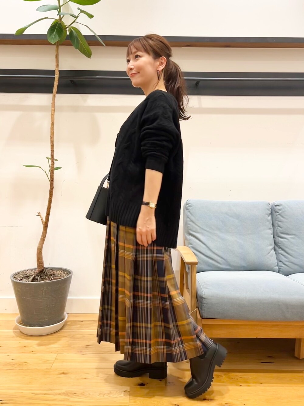 ブラック系のニット/セーター、ブルー系のスカート、ブラック系のショルダーバッグを着用したレディースの冬コーディネートの2枚目の写真