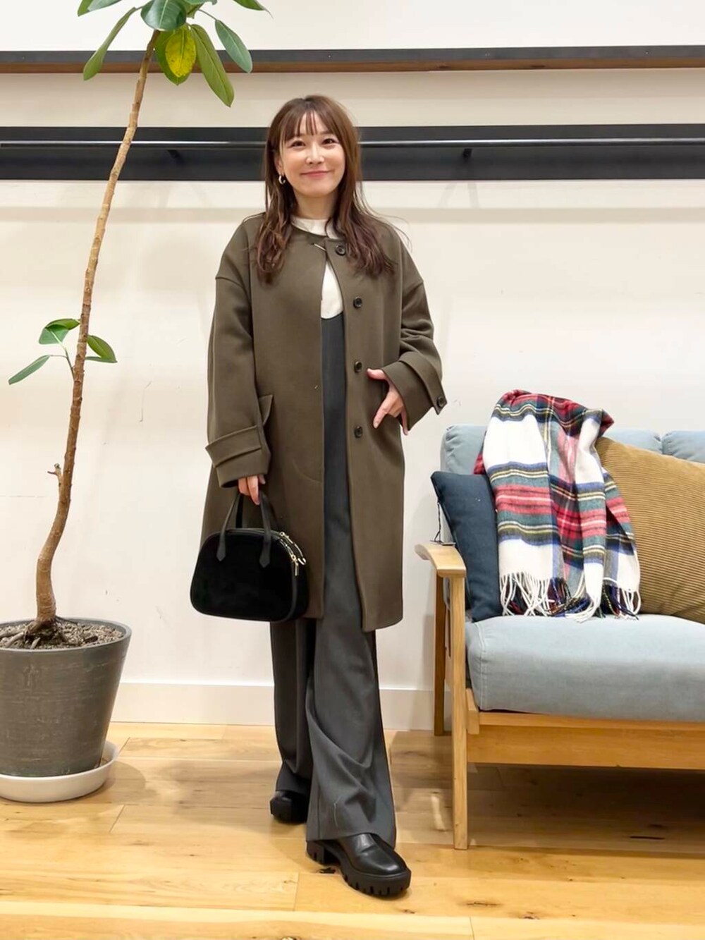 グリーン系のノーカラーコート、ホワイト系のニット/セーター、ブラック系のショルダーバッグを着用したレディースの冬コーディネートの3枚目の写真