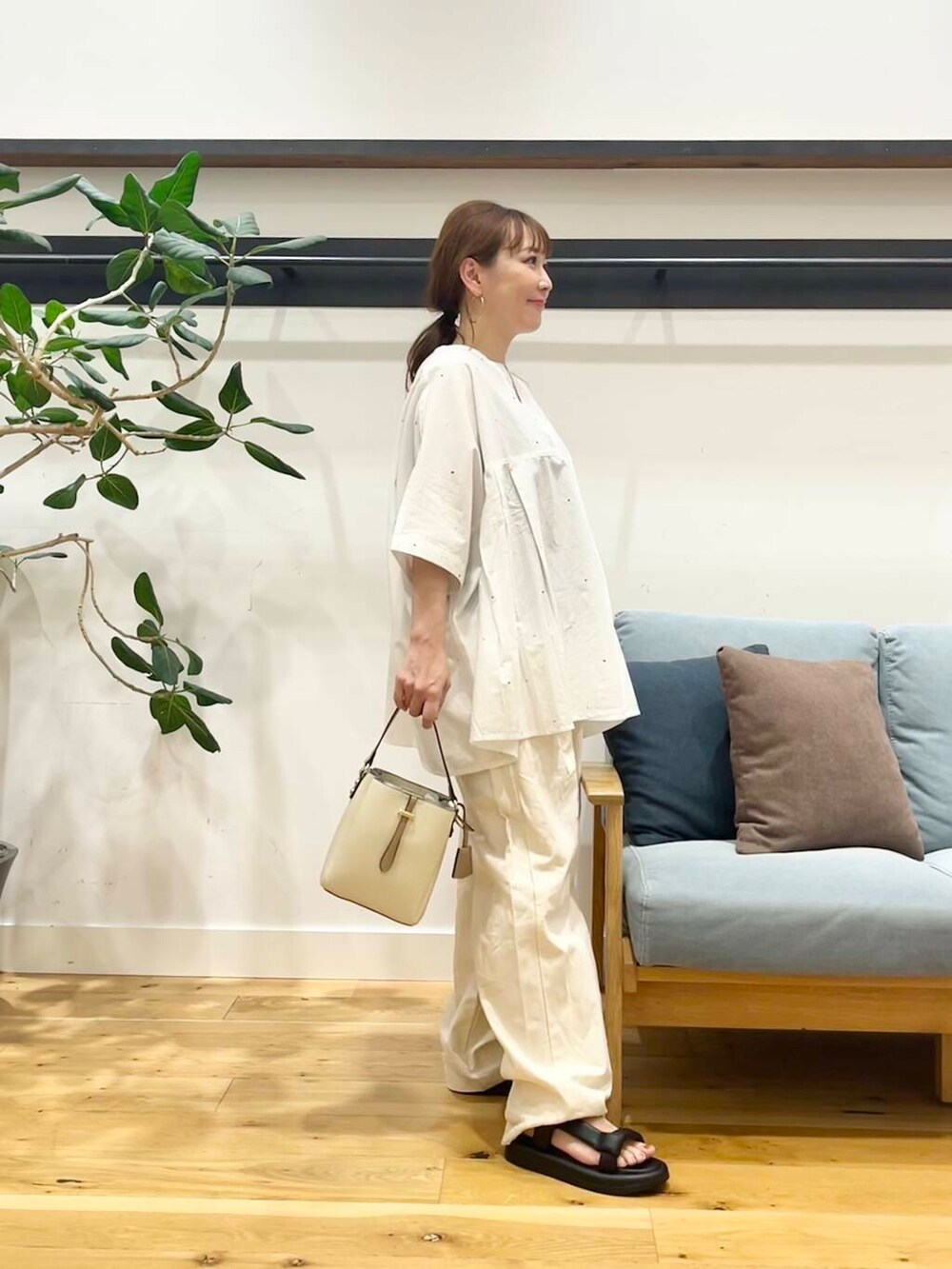 ホワイト系のショルダーバッグ、ブラック系のサンダル、ベージュ系のデニムパンツを着用したレディースの夏コーディネートの4枚目の写真