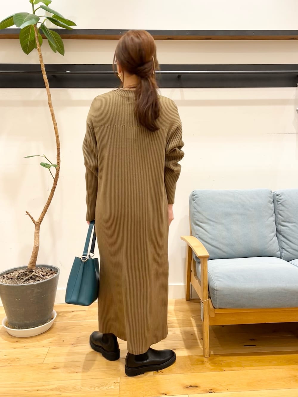 ブラウン系のワンピース、ブルー系のハンドバッグ、ブラック系のブーツを着用したレディースの冬コーディネートの3枚目の写真