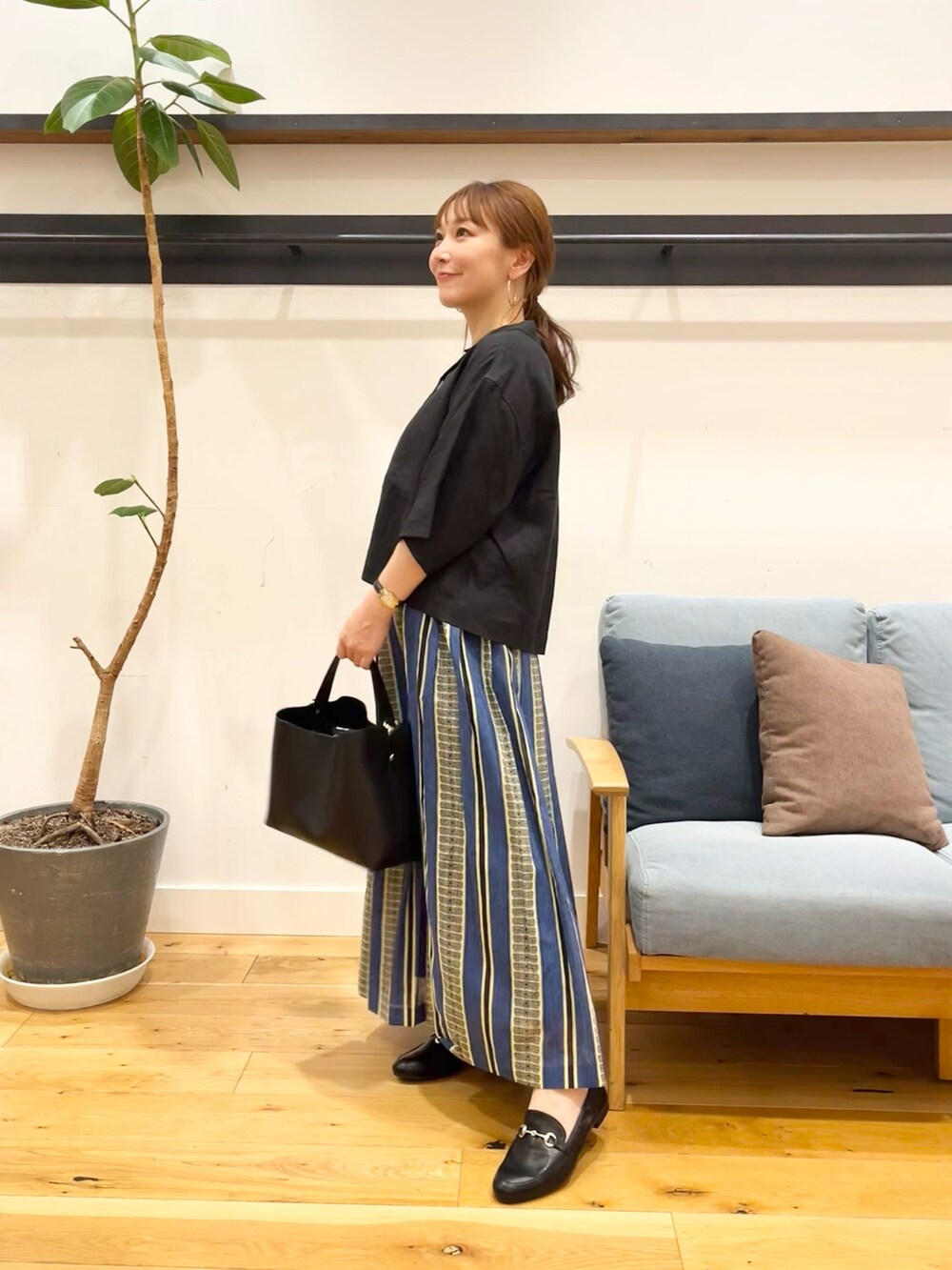ブラック系のシャツ/ブラウス、グリーン系のスカート、ブラック系のトートバッグを着用したレディースの春コーディネートの2枚目の写真