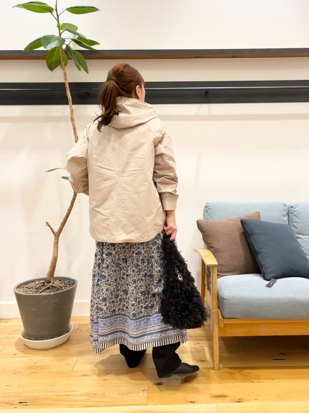 ベージュ系のマウンテンパーカー、ブルー系のワンピース、ブラック系のショルダーバッグを着用したレディースの冬コーディネートの3枚目の写真