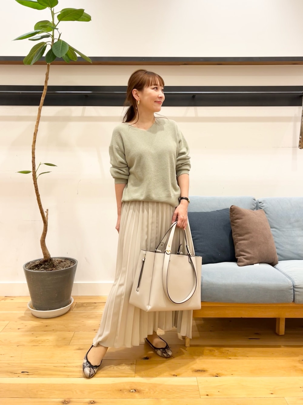 パープル系のニット/セーター、グレー系のスカート、グレー系のトートバッグを着用したレディースの冬コーディネートの2枚目の写真