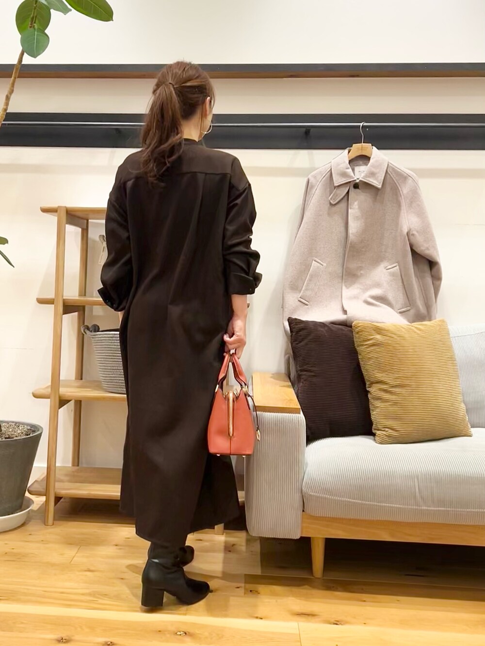 ブラウン系のワンピース、ブラック系のハンドバッグ、ブラック系のブーツを着用したレディースの冬コーディネートの3枚目の写真