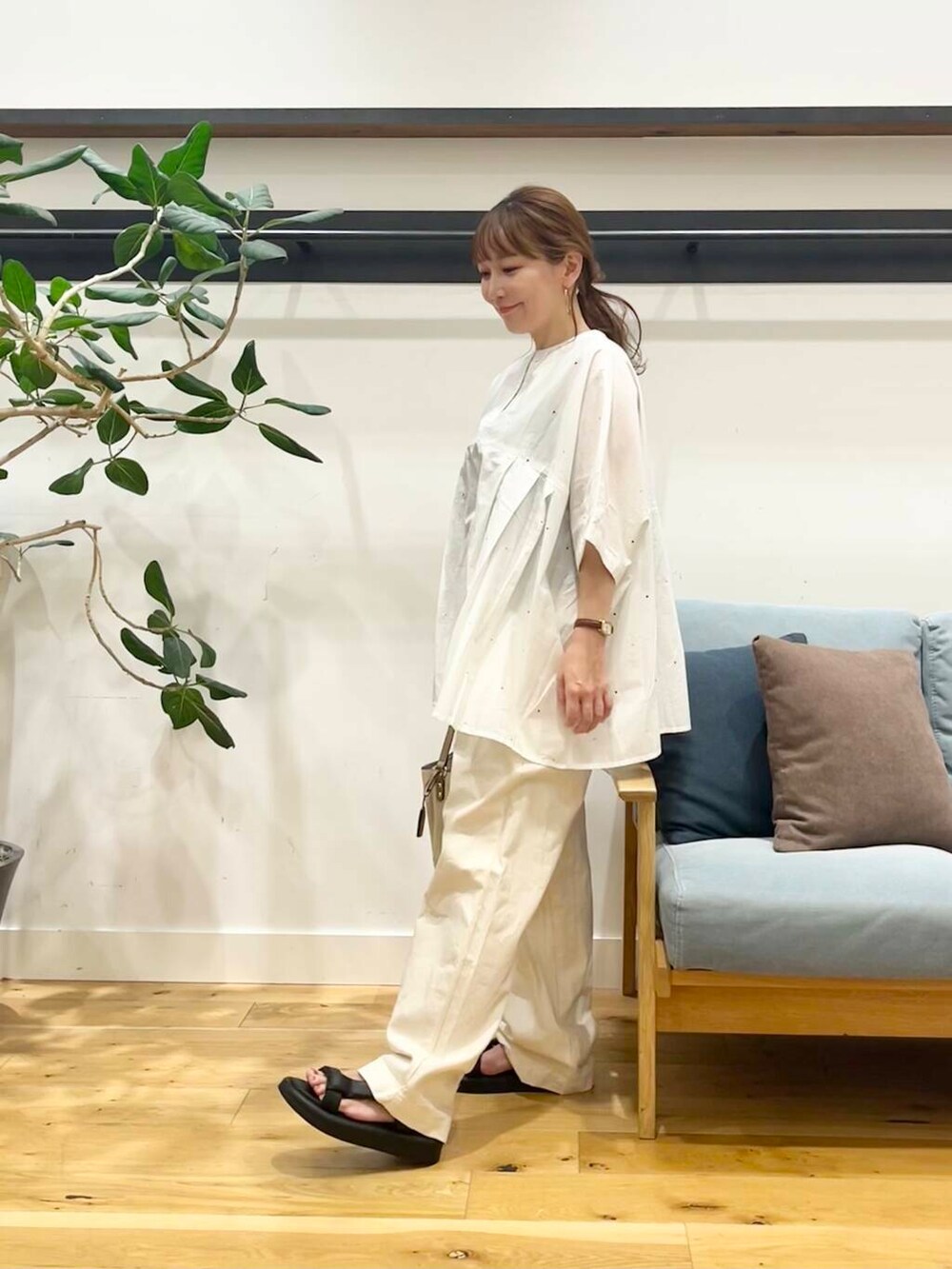 ホワイト系のショルダーバッグ、ブラック系のサンダル、ベージュ系のデニムパンツを着用したレディースの夏コーディネートの2枚目の写真
