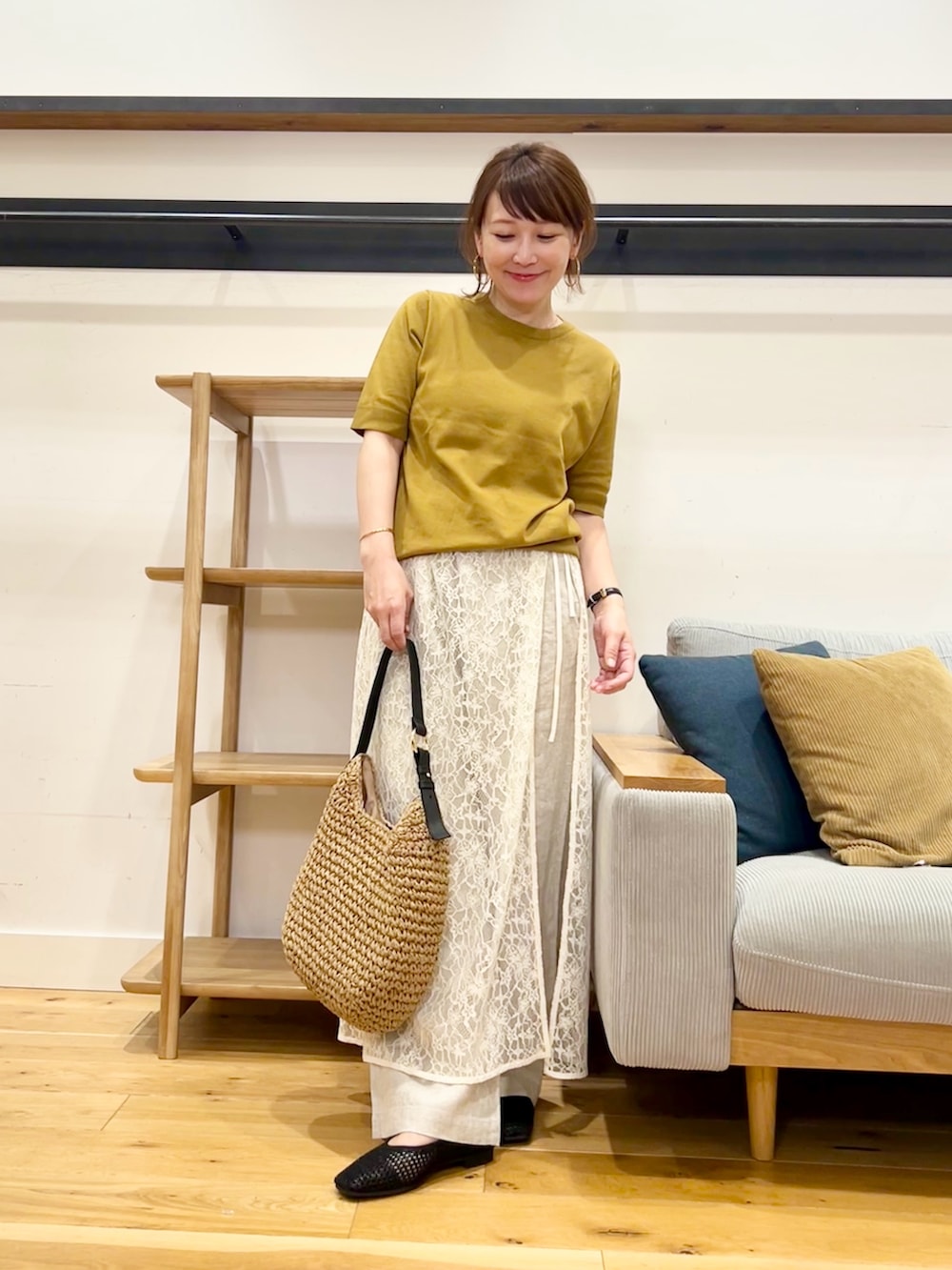 イエロー系のニット/セーター、ホワイト系のスカート、ベージュ系のトートバッグを着用したレディースの春コーディネートの4枚目の写真