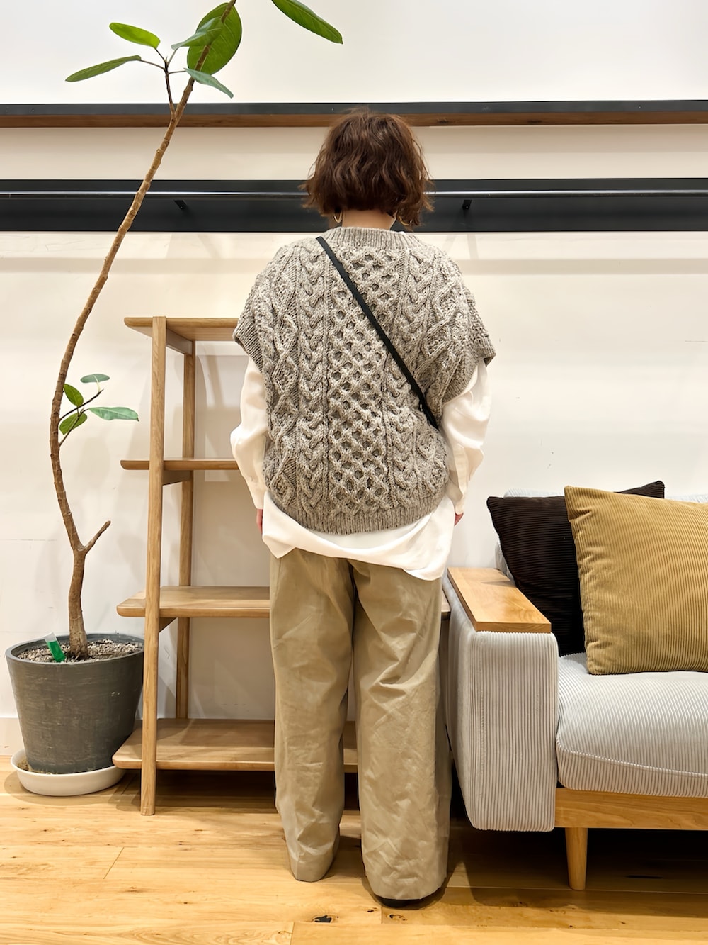 グレー系のニット/セーター、ホワイト系のシャツ/ブラウス、ブラック系のショルダーバッグを着用したレディースの秋コーディネートの3枚目の写真