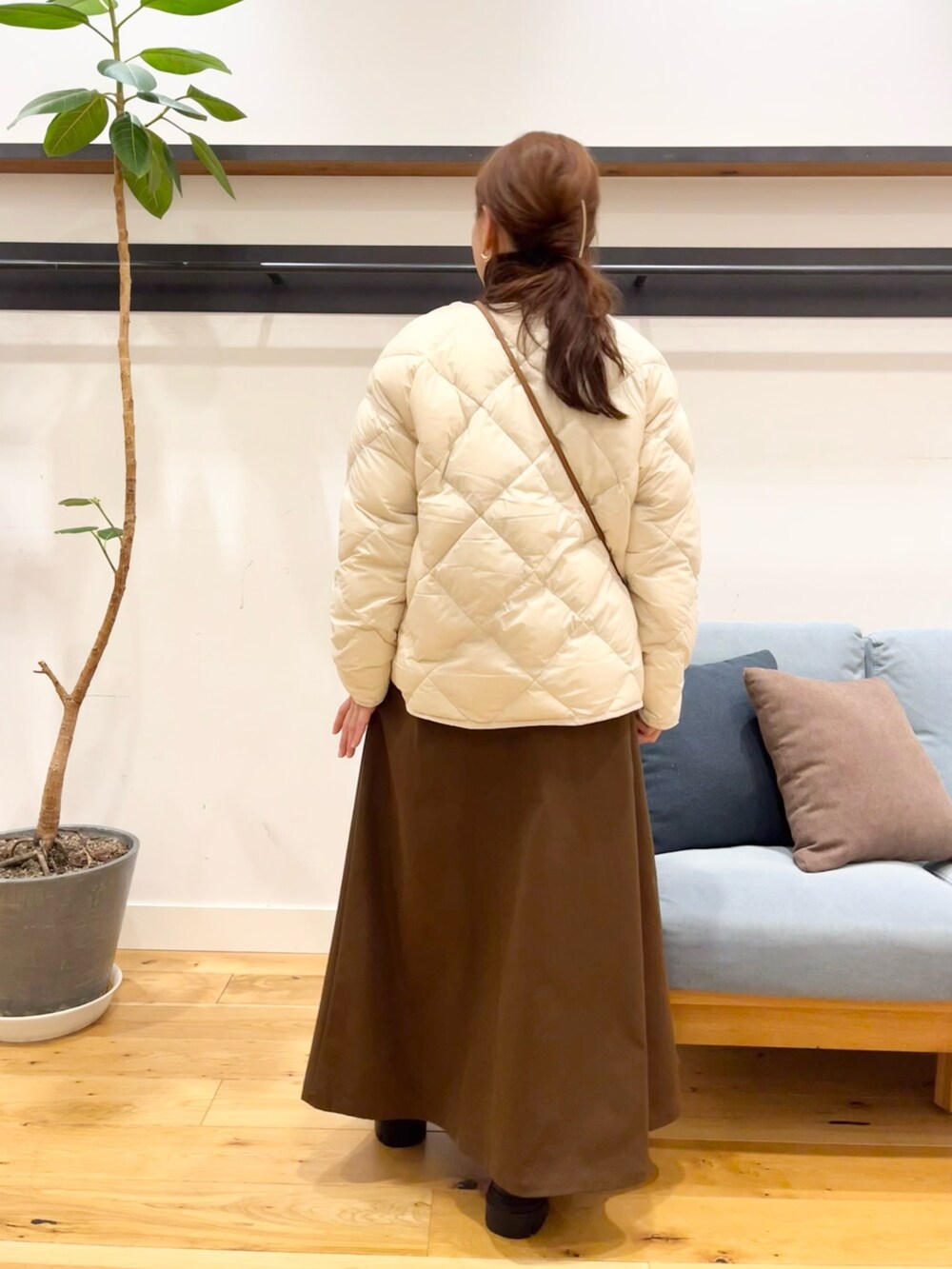 ホワイト系のダウンジャケット/コート、ブラック系のショルダーバッグ、ブラウン系のスカートを着用したレディースの冬コーディネートの4枚目の写真