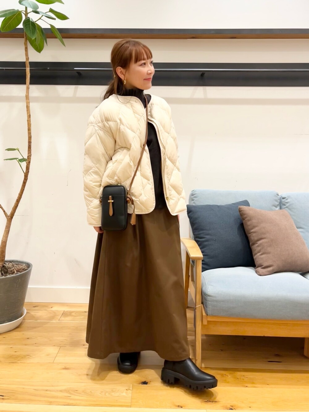 ホワイト系のダウンジャケット/コート、ブラック系のショルダーバッグ、ブラウン系のスカートを着用したレディースの冬コーディネートの2枚目の写真