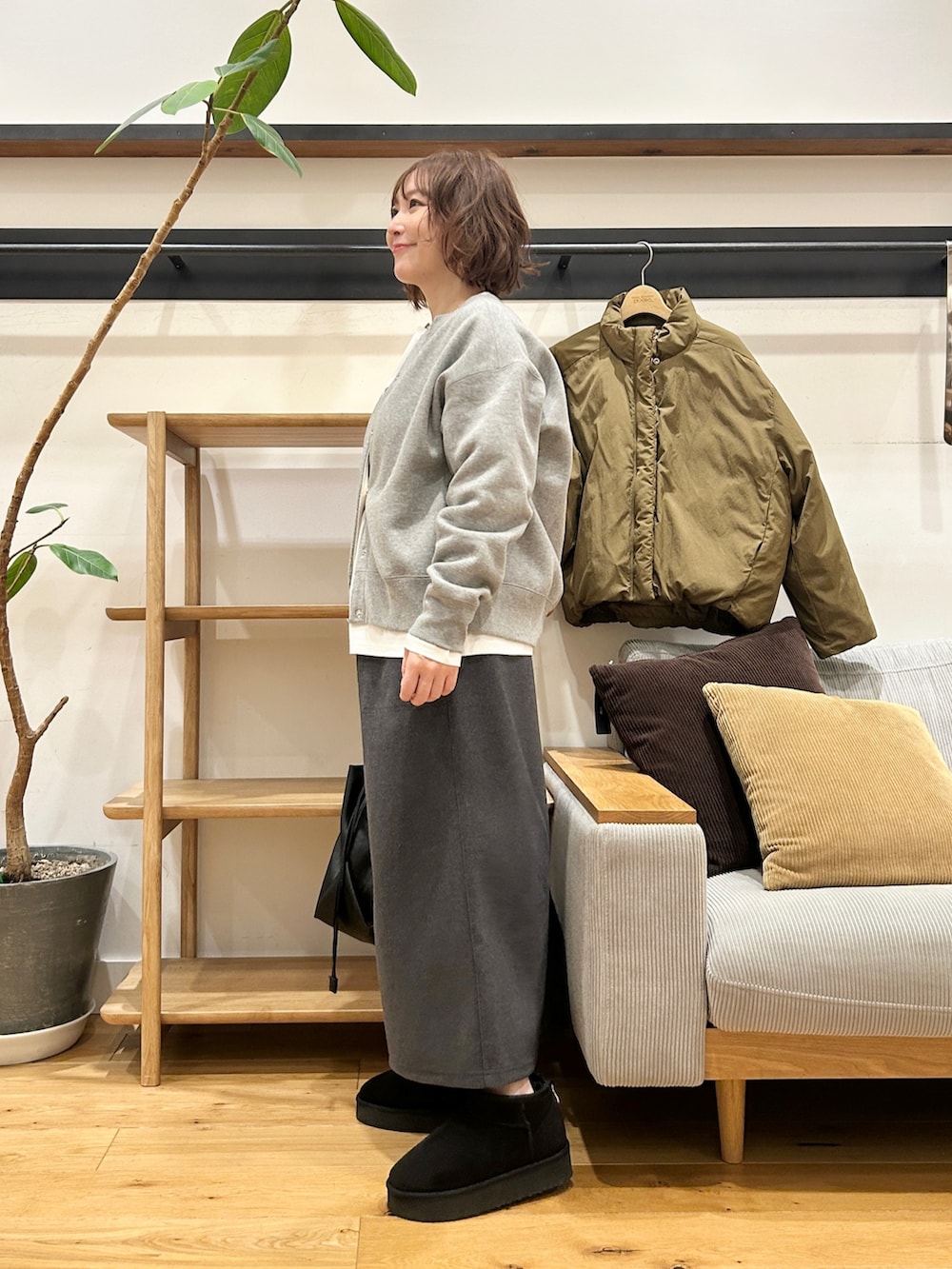 グリーン系のブルゾン、グレー系のカーディガン/ボレロ、グレー系のスカートを着用したレディースの冬コーディネートの2枚目の写真