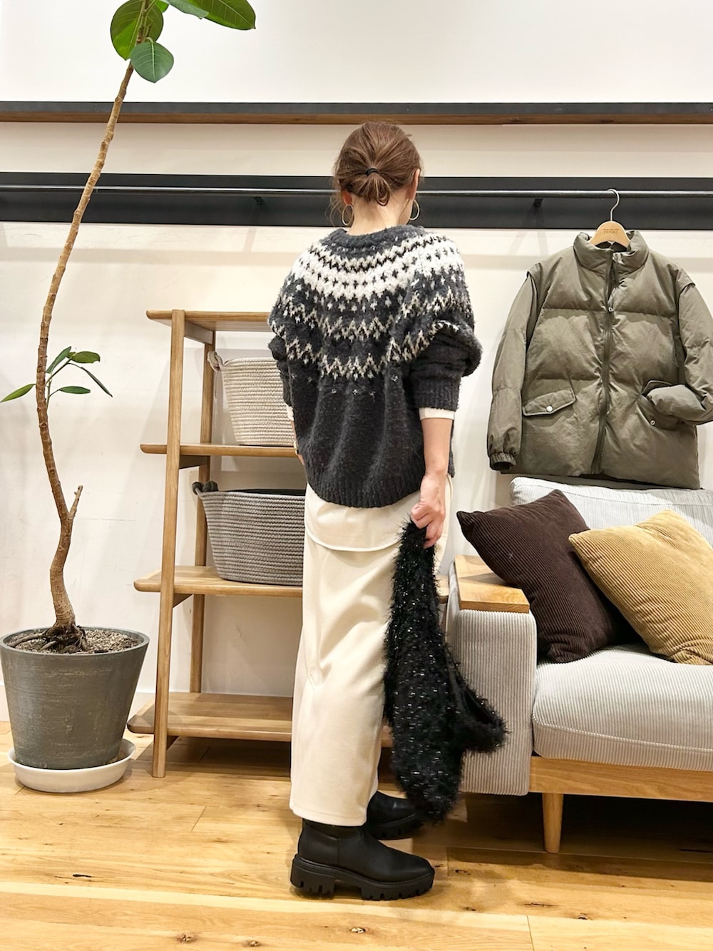 グレー系のニット/セーター、ブラウン系のトートバッグ、ホワイト系のスカートを着用したレディースの冬コーディネートの3枚目の写真