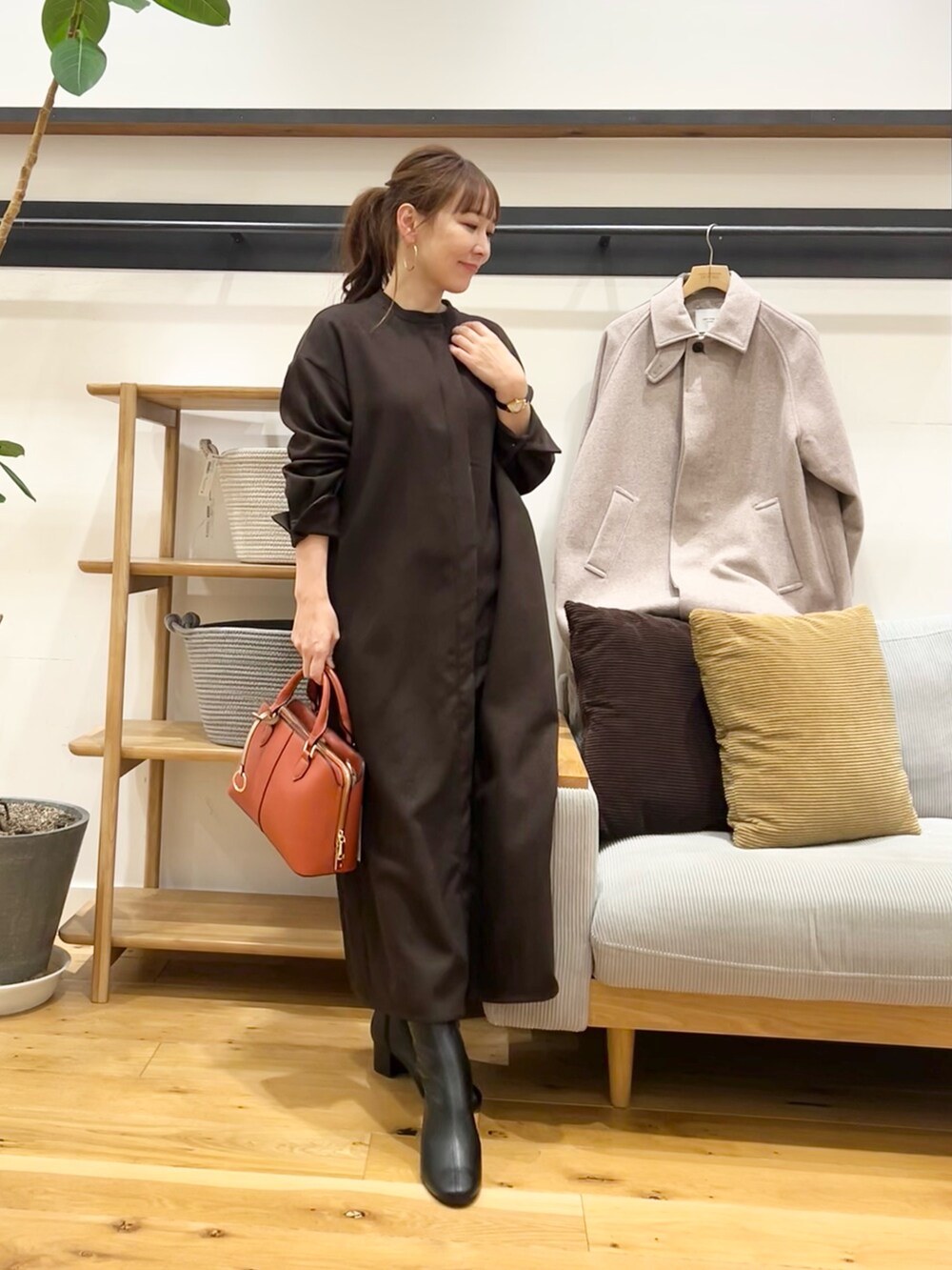 ブラウン系のワンピース、ブラック系のハンドバッグ、ブラック系のブーツを着用したレディースの冬コーディネートの2枚目の写真