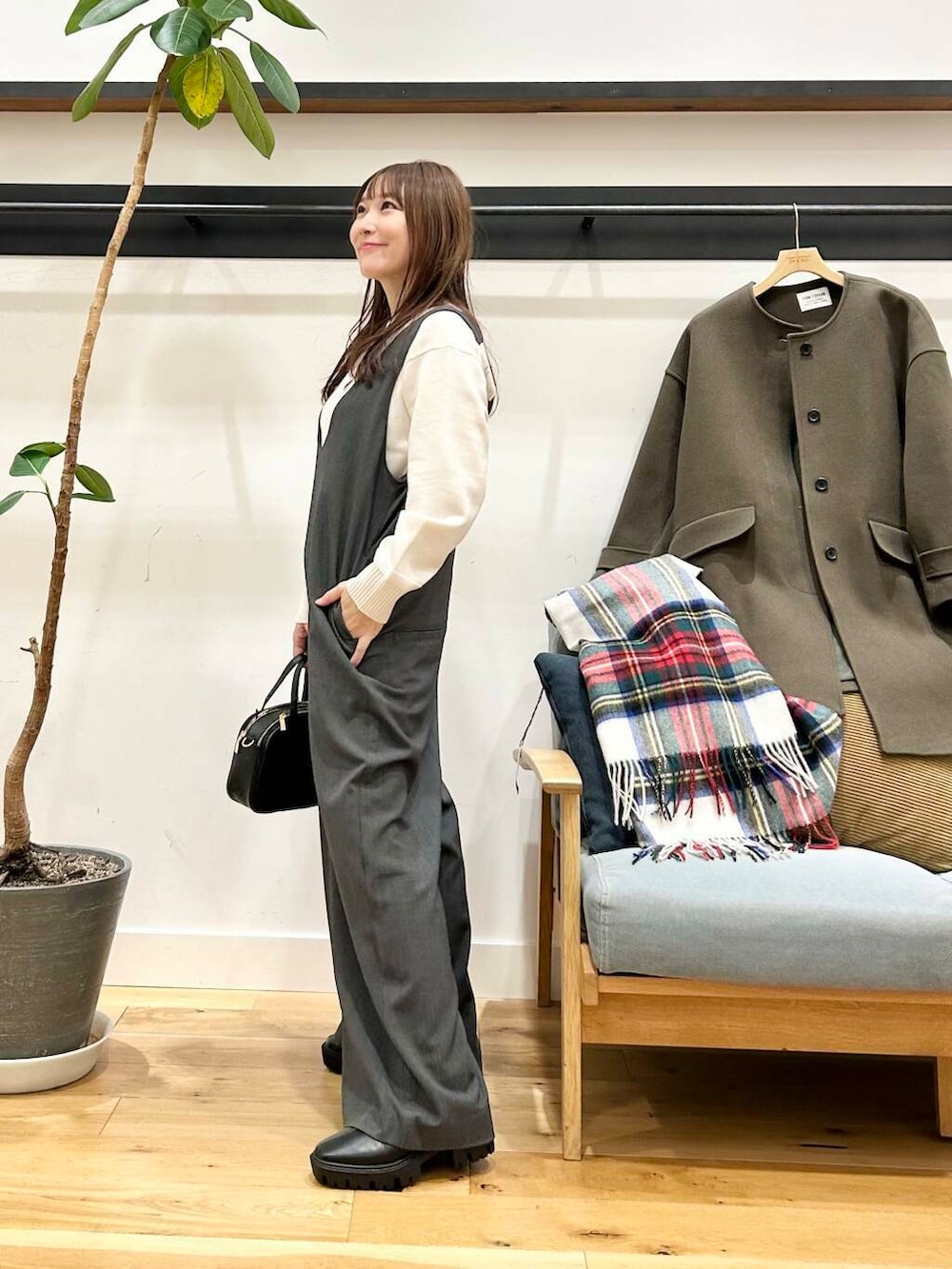 グリーン系のノーカラーコート、ホワイト系のニット/セーター、ブラック系のショルダーバッグを着用したレディースの冬コーディネートの6枚目の写真