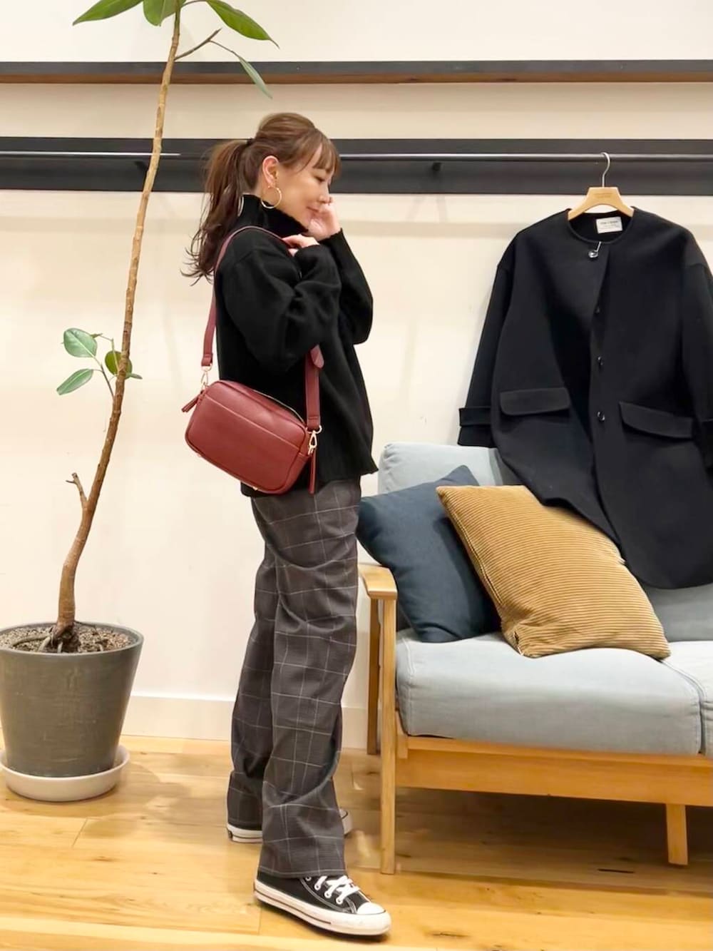 ブラック系のノーカラーコート、レッド系のショルダーバッグ、ブラック系のニット/セーターを着用したレディースの冬コーディネートの3枚目の写真