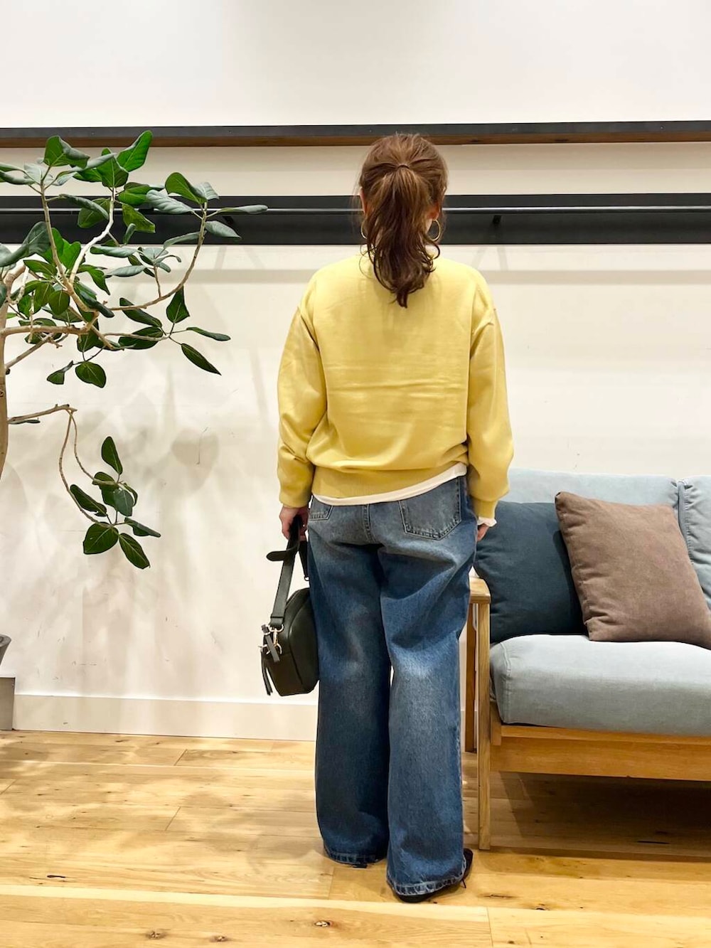 ブルー系のデニムパンツ、グリーン系のショルダーバッグ、ブラック系のその他シューズを着用したレディースの秋コーディネートの3枚目の写真