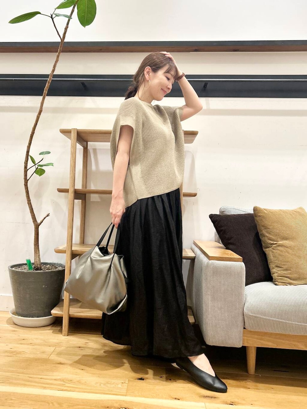 シルバー系のショルダーバッグ、ブラック系のパンプス、ベージュ系のニット/セーターを着用したレディースの夏コーディネートの3枚目の写真