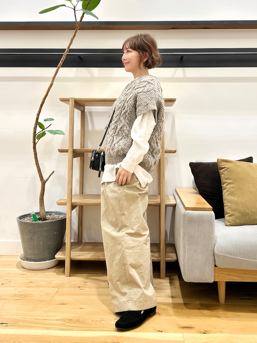 グレー系のニット/セーター、ホワイト系のシャツ/ブラウス、ブラック系のショルダーバッグを着用したレディースの秋コーディネートの2枚目の写真