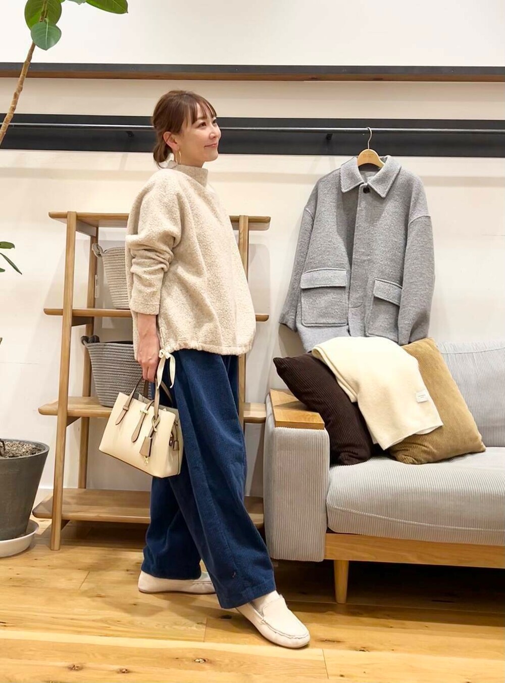 ホワイト系のハンドバッグ、グレー系のその他アウター、ホワイト系のスリッポンを着用したレディースの冬コーディネートの3枚目の写真