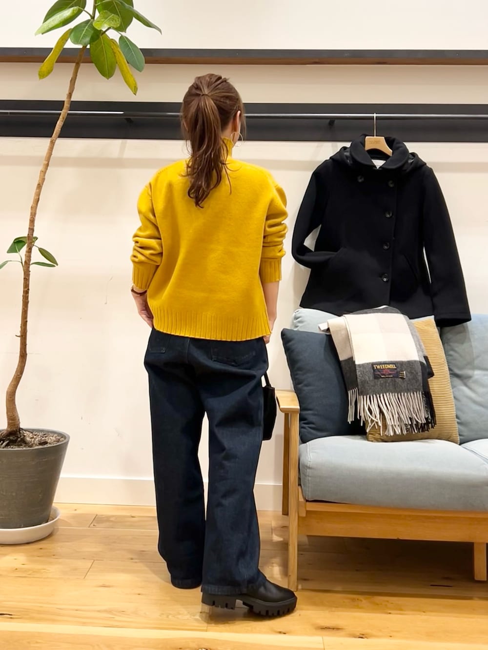 イエロー系のニット/セーター、ブルー系のデニムパンツ、ブラック系のショルダーバッグを着用したレディースの冬コーディネートの3枚目の写真