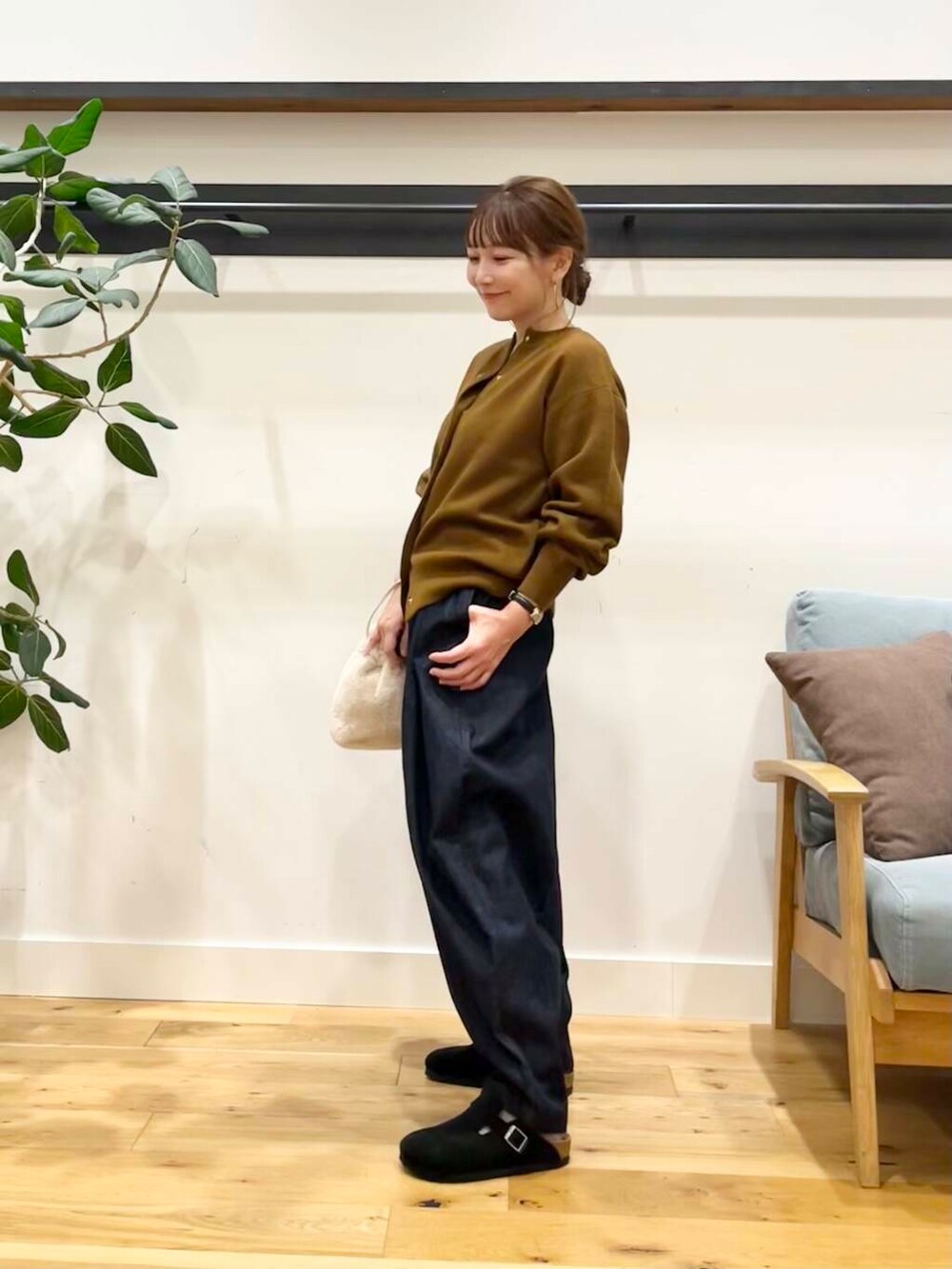 ブルー系のデニムパンツ、イエロー系のカーディガン/ボレロ、ホワイト系のショルダーバッグを着用したレディースの秋コーディネートの2枚目の写真