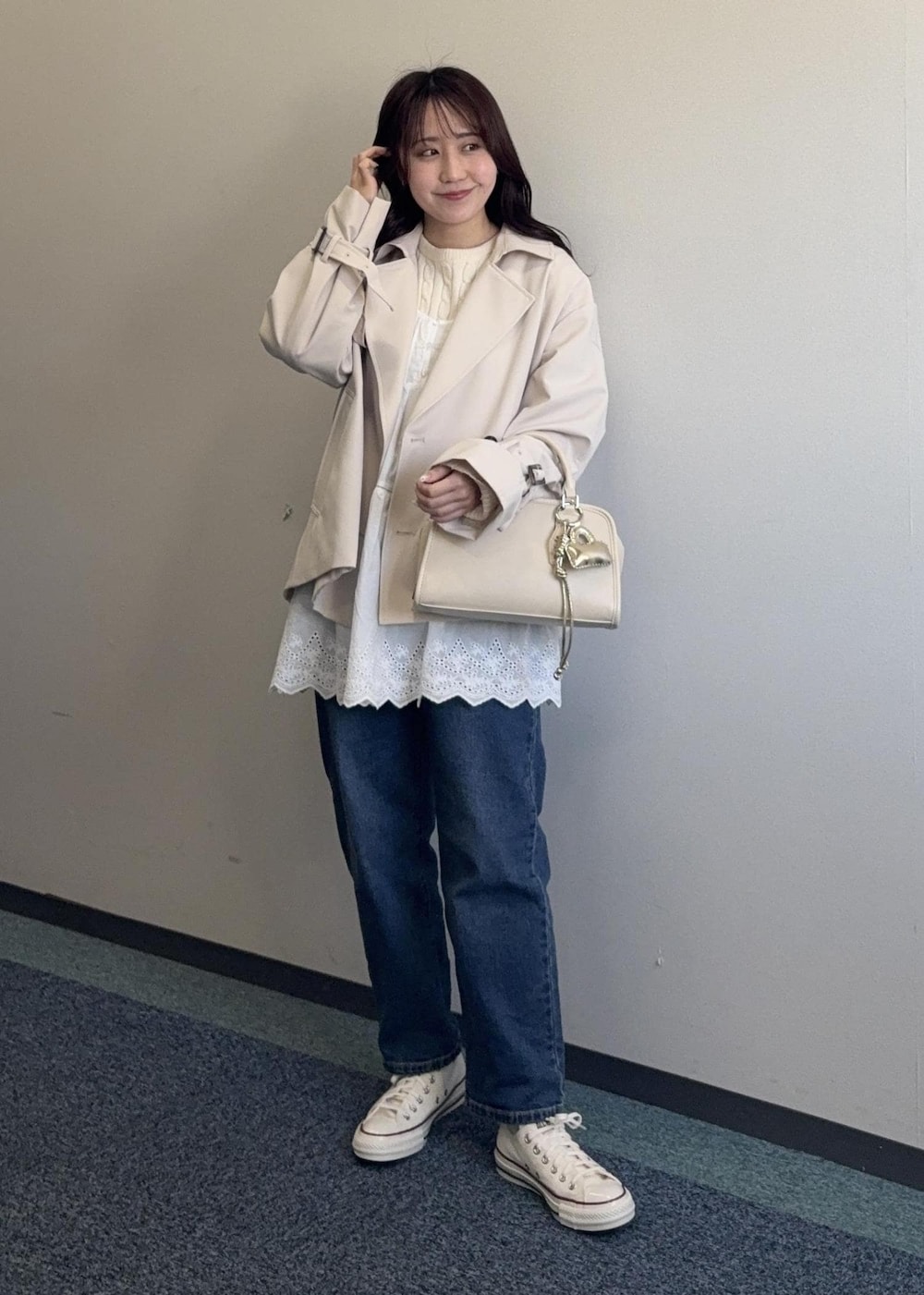 ホワイト系のニット/セーター、ベージュ系のボストンバッグ、ベージュ系のトレンチコートを着用したレディースの春コーディネートの5枚目の写真