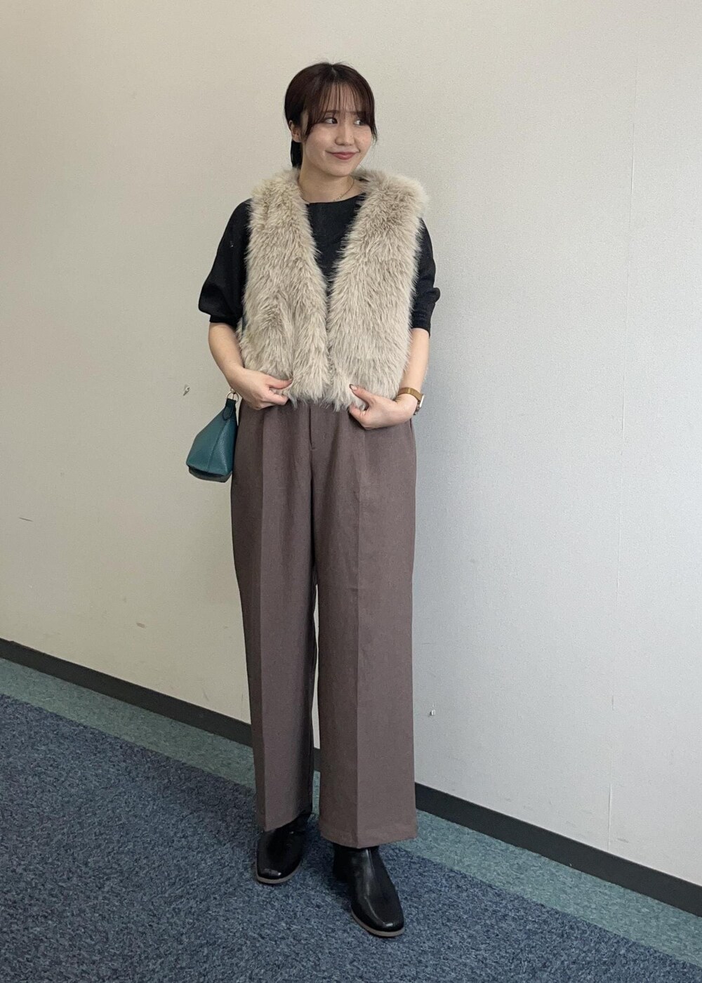 ブラウン系のショルダーバッグ、ベージュ系のスラックス、ベージュ系のベストを着用したレディースの秋コーディネートの3枚目の写真