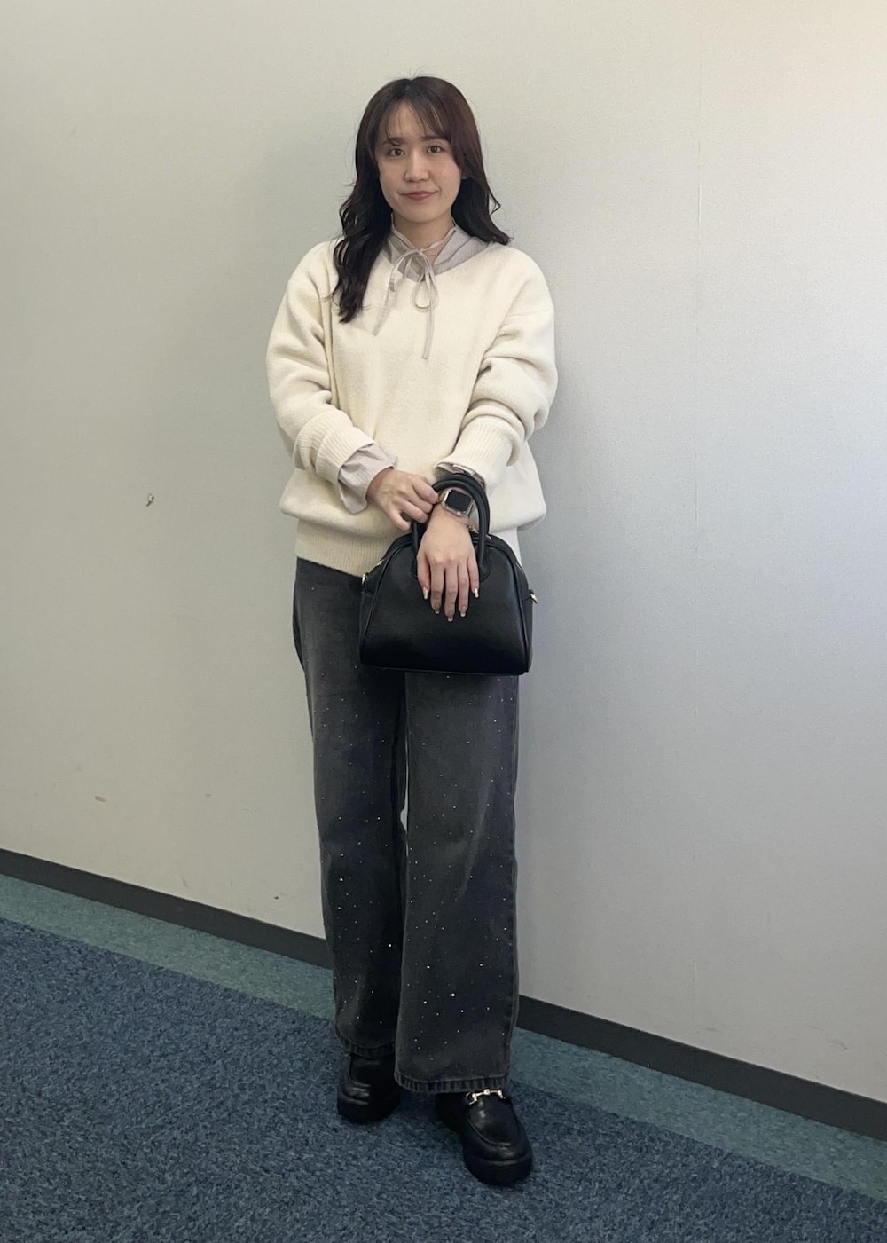 ブラック系のデニムパンツ、ホワイト系のニット/セーター、ブラック系のボストンバッグを着用したレディースの冬コーディネートの3枚目の写真