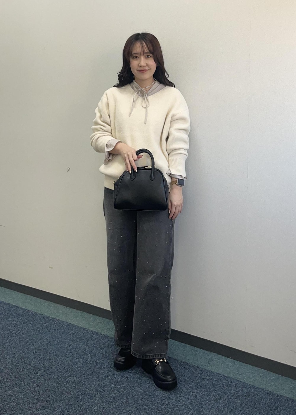 ブラック系のデニムパンツ、ホワイト系のニット/セーター、ブラック系のボストンバッグを着用したレディースの冬コーディネートの4枚目の写真