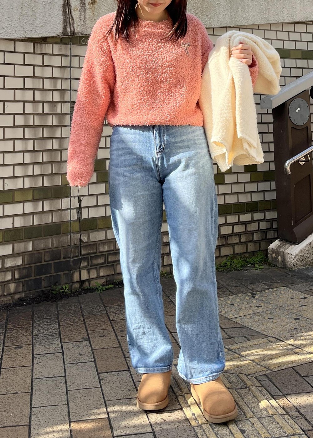 ブルー系のデニムパンツ、ピンク系のニット/セーター、シルバー系のブローチ/コサージュを着用したレディースの冬コーディネートの3枚目の写真