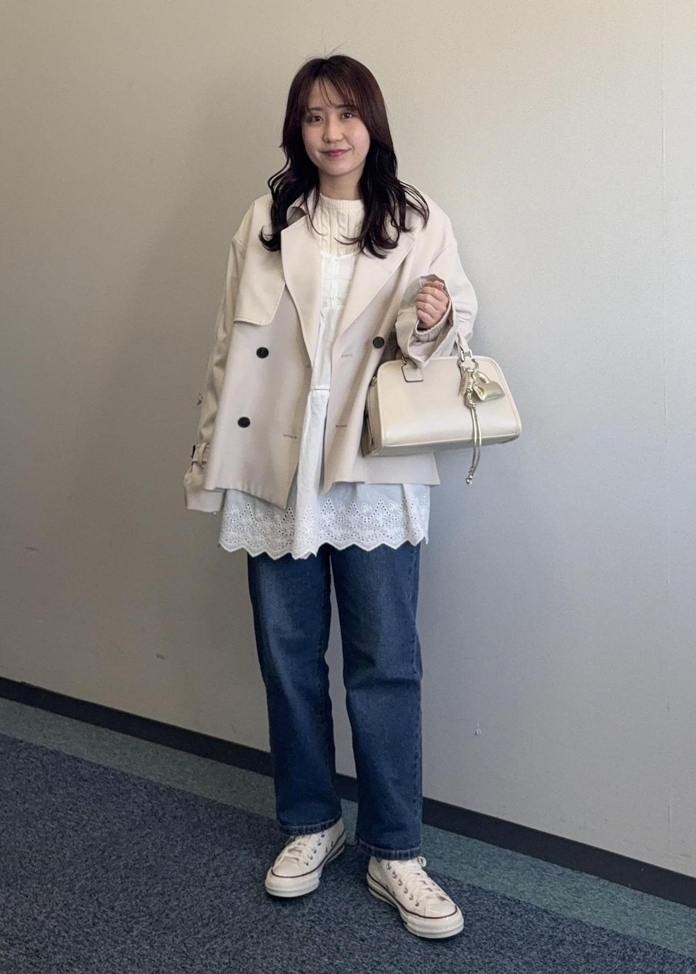 ホワイト系のニット/セーター、ベージュ系のボストンバッグ、ベージュ系のトレンチコートを着用したレディースの春コーディネートの6枚目の写真