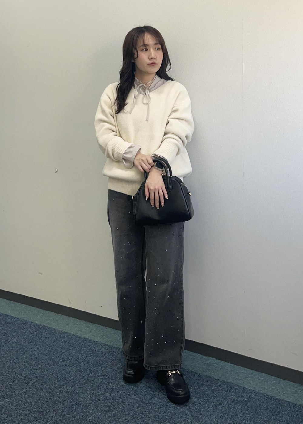 ブラック系のデニムパンツ、ホワイト系のニット/セーター、ブラック系のボストンバッグを着用したレディースの冬コーディネートの2枚目の写真