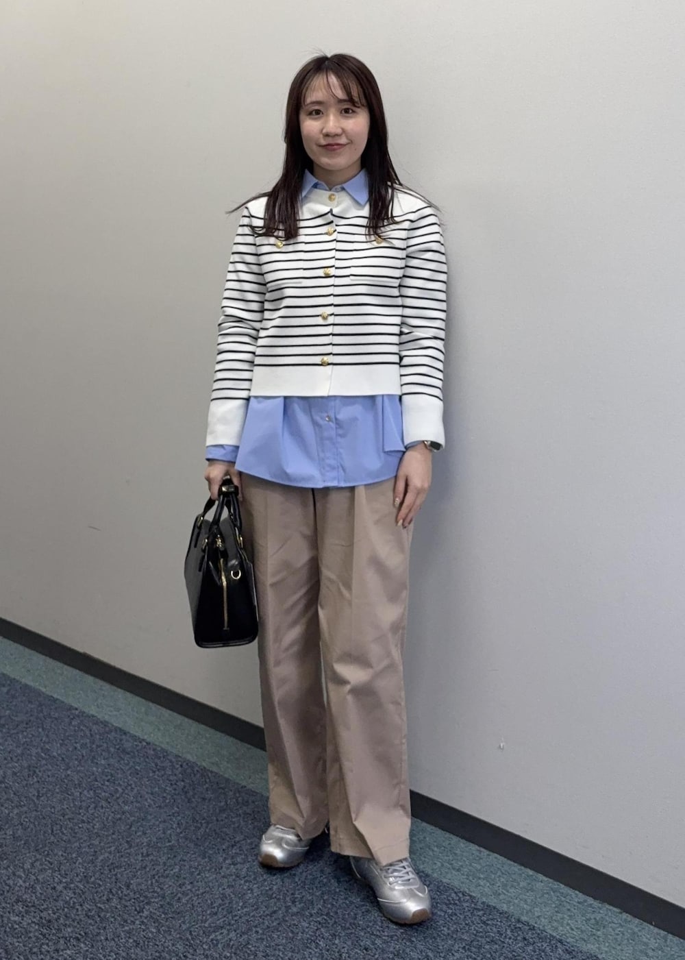 シルバー系のスニーカー、ブラック系のボストンバッグ、ベージュ系のチノパンツを着用したレディースの冬コーディネートの2枚目の写真