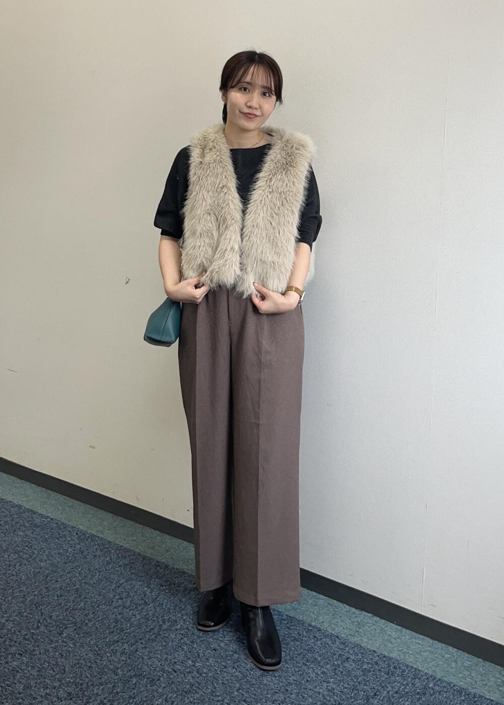 ブラウン系のショルダーバッグ、ベージュ系のスラックス、ベージュ系のベストを着用したレディースの秋コーディネートの2枚目の写真