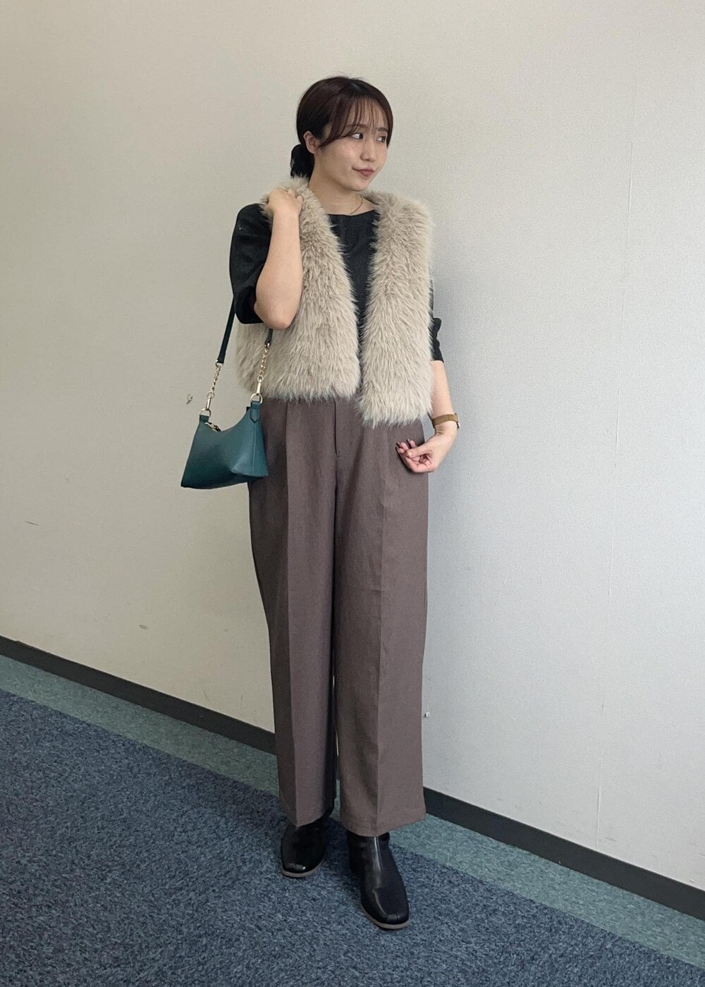 ブラウン系のショルダーバッグ、ベージュ系のスラックス、ベージュ系のベストを着用したレディースの秋コーディネートの4枚目の写真