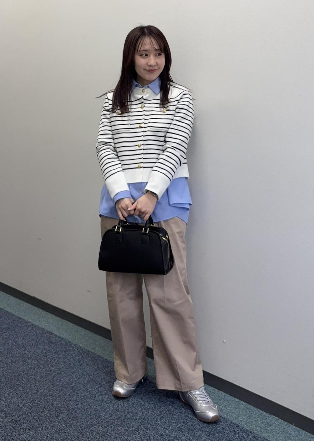 シルバー系のスニーカー、ブラック系のボストンバッグ、ベージュ系のチノパンツを着用したレディースの冬コーディネートの4枚目の写真