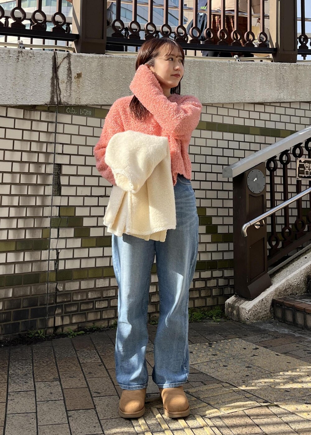 ブルー系のデニムパンツ、ピンク系のニット/セーター、シルバー系のブローチ/コサージュを着用したレディースの冬コーディネートの2枚目の写真