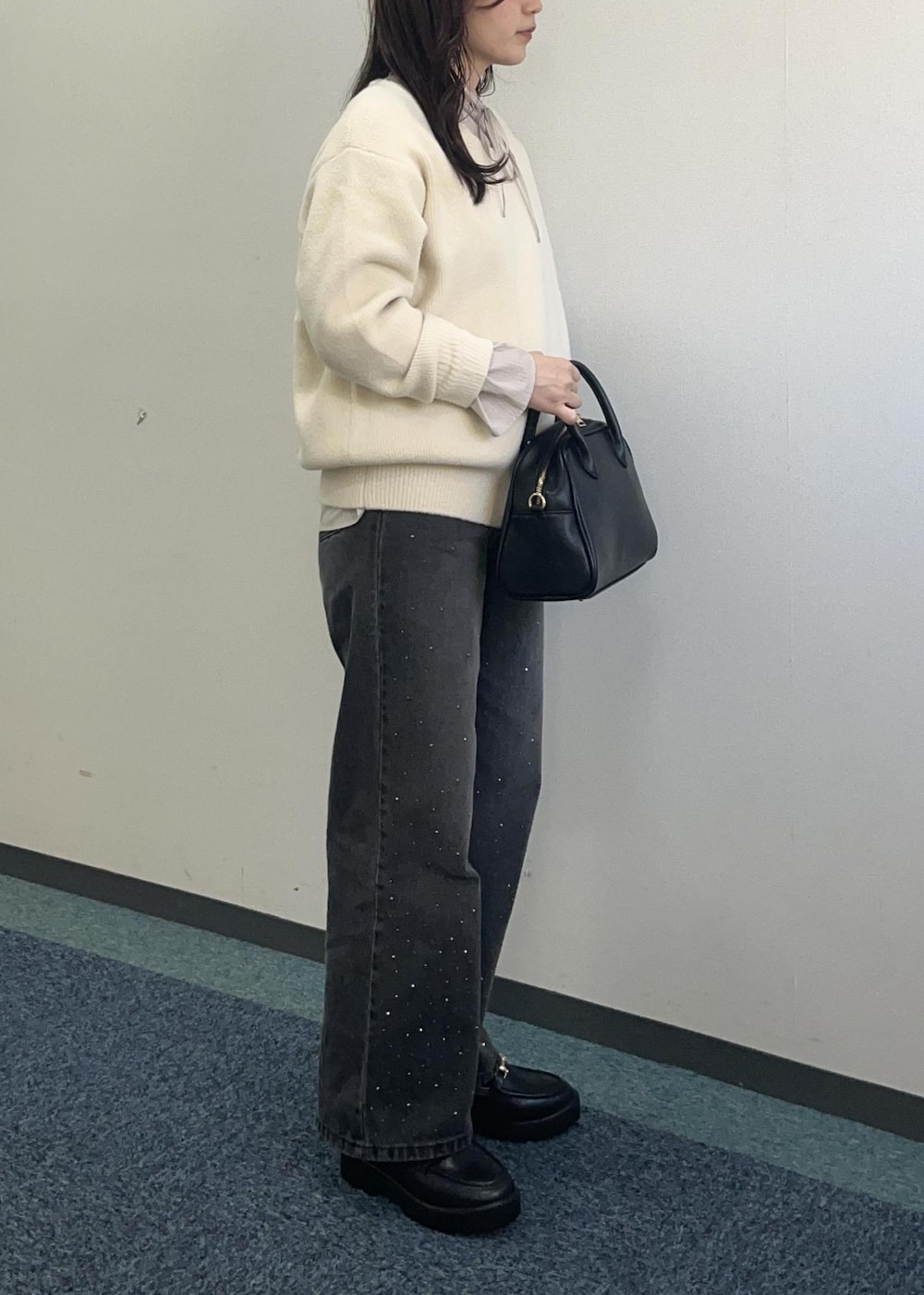 ブラック系のデニムパンツ、ホワイト系のニット/セーター、ブラック系のボストンバッグを着用したレディースの冬コーディネートの5枚目の写真