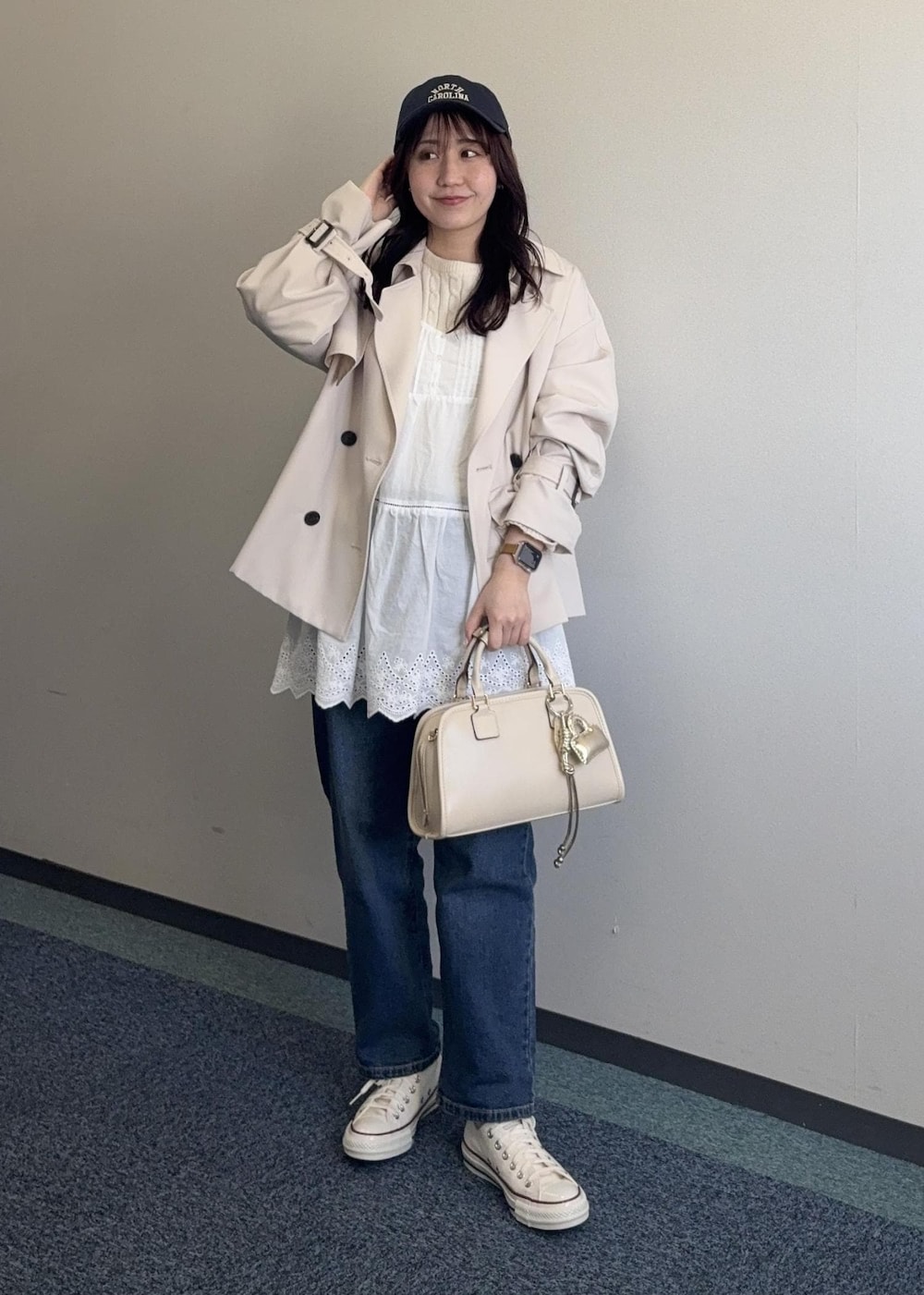 ホワイト系のニット/セーター、ベージュ系のボストンバッグ、ベージュ系のトレンチコートを着用したレディースの春コーディネートの2枚目の写真