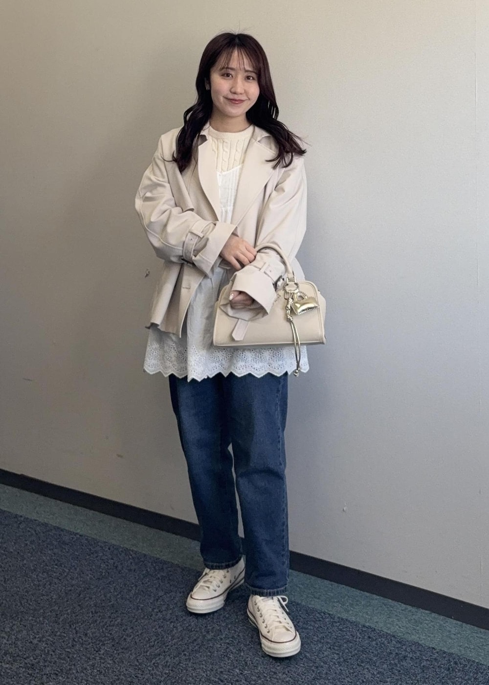 ホワイト系のニット/セーター、ベージュ系のボストンバッグ、ベージュ系のトレンチコートを着用したレディースの春コーディネートの4枚目の写真